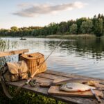 Ein Holzsteg am See mit Angelgerät und einem gefangenen Fisch auf einem Schneidebrett zur Wertschätzung der Verwertung.